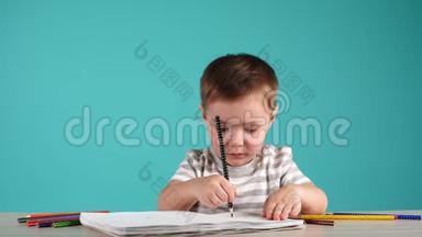 快乐的孩子用铅笔在相册里画画，孤立在蓝色上。